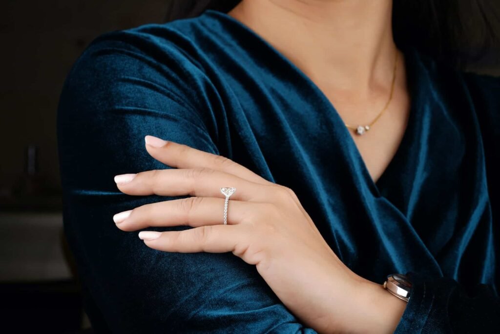 Woman in dark velvet wearing a lab diamond solitaire ring and pendant necklace